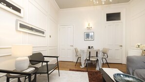 Una sala de estar moderna con comedor, paredes blancas y una araña.