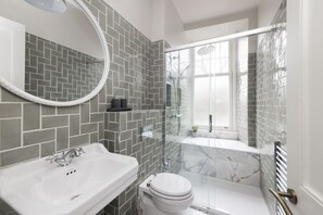 A modern bathroom with a white sink, a toilet, and a glass-enclosed shower area.