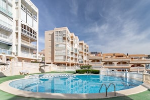 Un hotel con piscina, diversi balconi e cielo sereno.