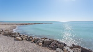 Een kustlandschap met een rotsachtige kustlijn, rustige zee en heldere lucht.