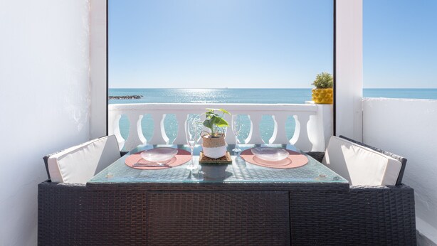Een balkon met een tafel gedekt voor twee, met uitzicht op de zee.