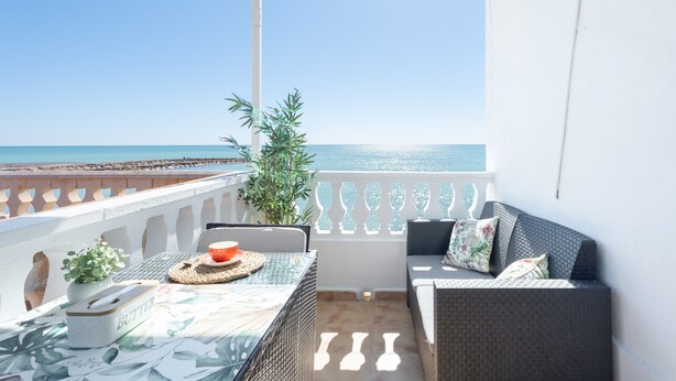 Un balcon avec une table, des chaises, un canapé et une plante en pot.