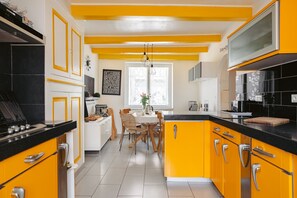 Una cucina moderna con mobili gialli, un piano di lavoro nero e un'area pranzo con tavolo e sedie.