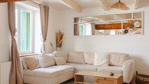 Un salon chaleureux avec un canapé d’angle, une table basse en bois et un grand miroir.