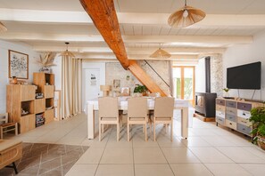 Ein modernes Wohnzimmer mit Esstisch, Stühlen, Fernseher und Kamin.