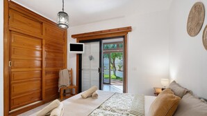 A bedroom with a bed, a wooden wardrobe, a television, and a view through a glass door. - Vacation Home 'Casa Relax Marine' with Shared Pool, Wi-Fi and Air Conditioning (Costa del Silencio Arona)