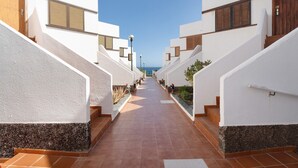 A corridor with white walls, wooden doors, and tiled flooring leading to a blue sky. - Vacation Home 'Casa Relax Marine' with Shared Pool, Wi-Fi and Air Conditioning (Costa del Silencio Arona)