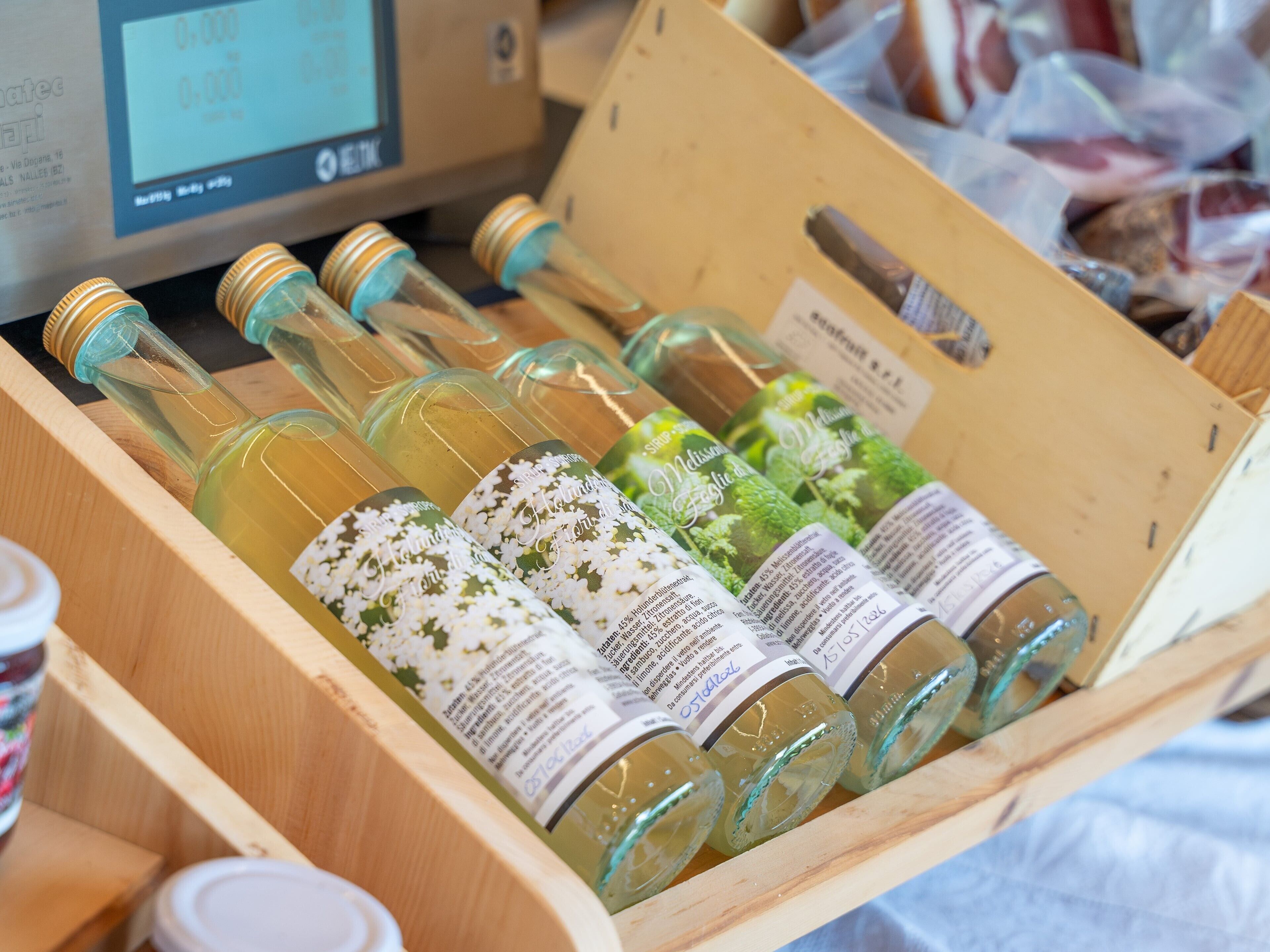Une caisse en bois contenant plusieurs bouteilles de vin blanc, toutes étiquetées, un écran d’ordinateur et une boîte en carton munie d’une poignée.