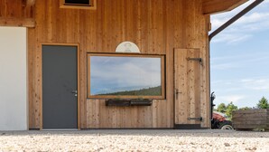 A wooden building with a large window, a door, and a small window above the door.