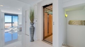 A modern hotel lobby with a large vase, a glass elevator, and a view of the sky through the windows. - Apartment 'Modern 3 Bed, Sea View and Pool' with Shared Pool, Wi-Fi and Air Conditioning (Estepona)