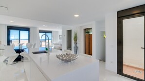 A modern kitchen with a central island, white cabinetry, and a view to the outside. - Apartment 'Modern 3 Bed, Sea View and Pool' with Shared Pool, Wi-Fi and Air Conditioning (Estepona)