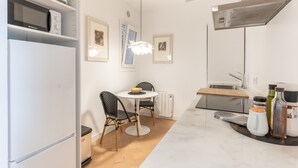 Eine kleine Küche mit Kühlschrank, Mikrowelle und Esstisch mit Stühlen.