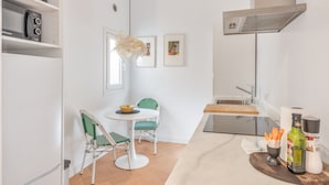 A compact kitchen with a dining area, a microwave, a kettle, and a small table with chairs.