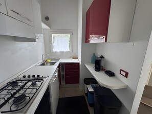 A compact kitchen with a gas stove, sink, and a window with a view. - Apartment 'Appartamento Sea View' with Shared Pool, Private Terrace and Air Conditioning (Arzachena)