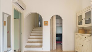 A staircase leading to a kitchen area, a cabinet with drawers, and an air conditioning unit. - Apartment 'Appartamento Sea View' with Shared Pool, Private Terrace and Air Conditioning (Arzachena)