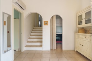 A staircase leading to a kitchen area, a cabinet with drawers, and an air conditioning unit. - Apartment 'Appartamento Sea View' with Shared Pool, Private Terrace and Air Conditioning (Arzachena)