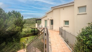 A residential building with a balcony, a view of the surrounding greenery, and a clear sky. - Apartment 'Appartamento Sea View' with Shared Pool, Private Terrace and Air Conditioning (Arzachena)