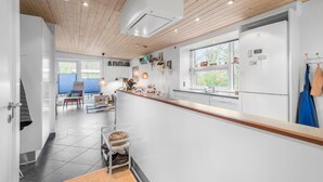 A modern kitchen with white cabinets, a wooden ceiling, and a window providing natural light.
