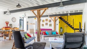Un interior moderno con comedor, asientos, una escalera y obras de arte en las paredes.