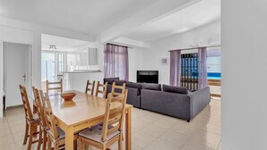 Ein modernes Wohnzimmer mit Essbereich, einer Couch, einem Fernseher und Meerblick.