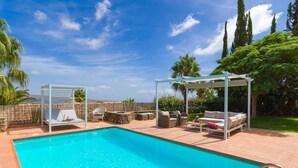 Ein Schwimmbecken mit Pergola, Liegestühlen und einer überdachten Sitzgelegenheit.