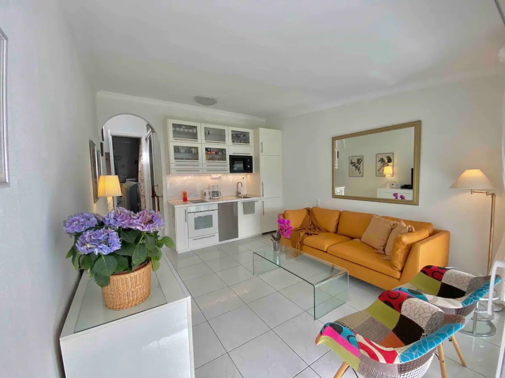 Un espacio habitable compacto con kitchenette, un sofá, una mesa de centro y una silla.