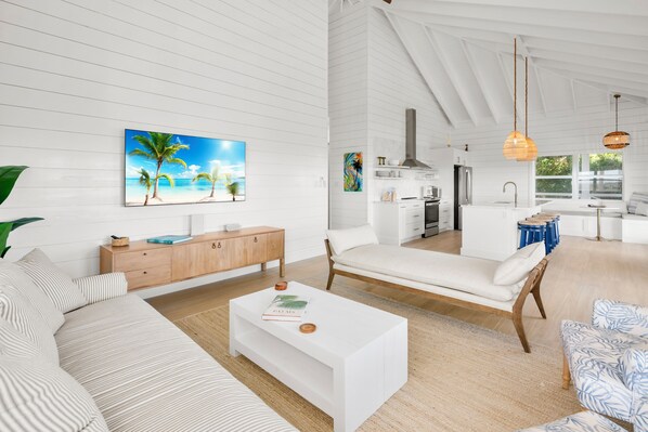 Un salón amplio con un sofá blanco, una mesa de centro y un cuadro de una playa.