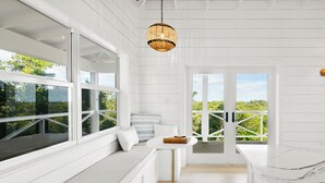 Una cocina moderna con armarios blancos, una mesa redonda y vistas amplias a través de grandes ventanales.