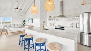 Una cocina moderna con armarios blancos, una isla grande con taburetes e iluminación colgante.