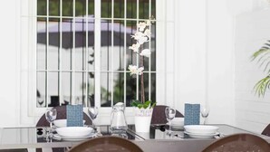 A dining table set with plates, glasses, and a vase with flowers.