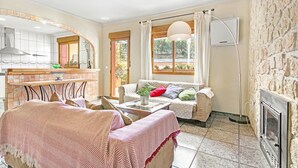 A cozy living room with a fireplace, a sofa, a coffee table, and a dining area with a tiled backsplash.