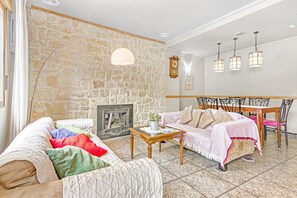 A cozy living room with a stone wall, fireplace, wooden furniture, and hanging lights. - Holiday Home 'Ca Lluis' with Mountain View, Wi-Fi and Air Conditioning (Vall De Laguart)