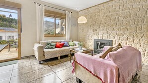 A cozy living room with a stone wall, a sofa with colorful pillows, a coffee table, and a fireplace.