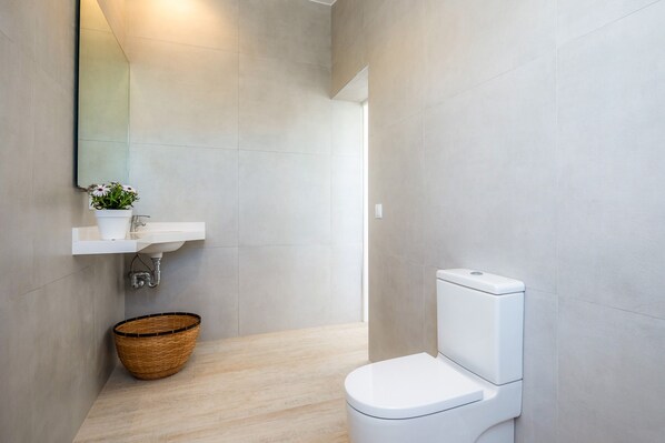 A modern bathroom with a toilet, sink, and a mirror.