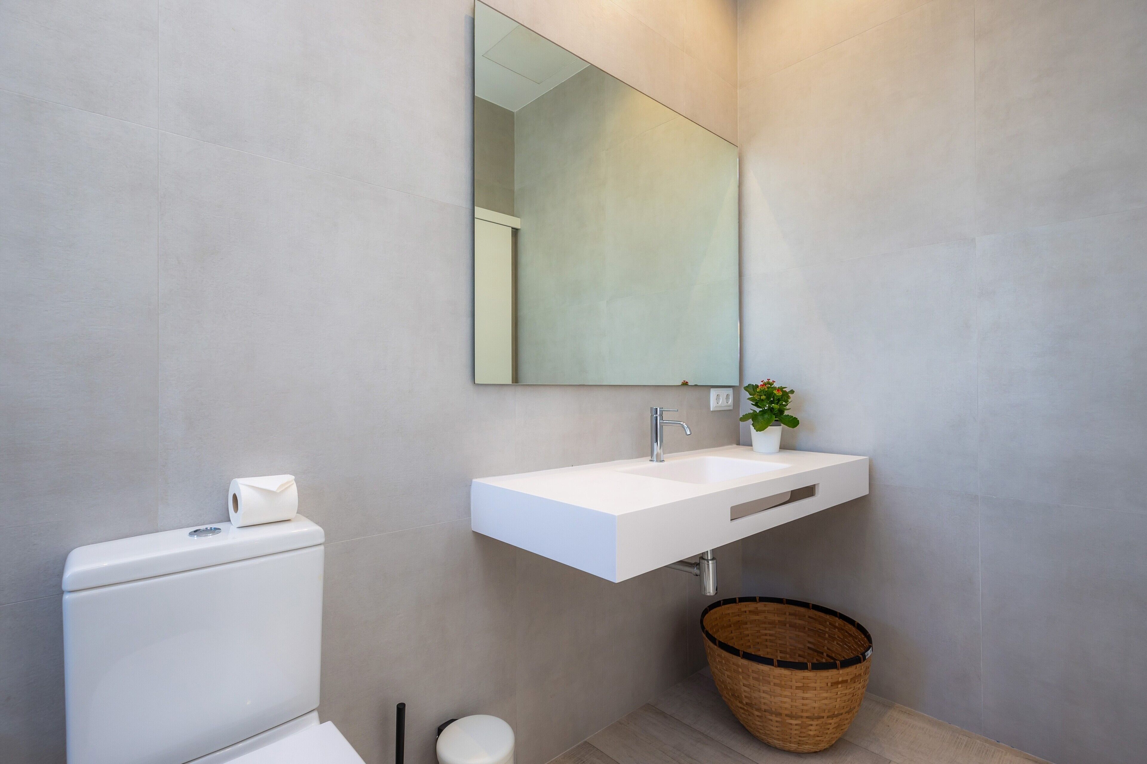 Ein modernes Badezimmer mit Toilette, Waschbecken und Spiegel.