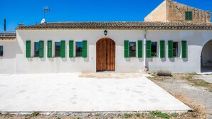 Un edificio con puerta de madera en el centro, contraventanas verdes y tejado de tejas.