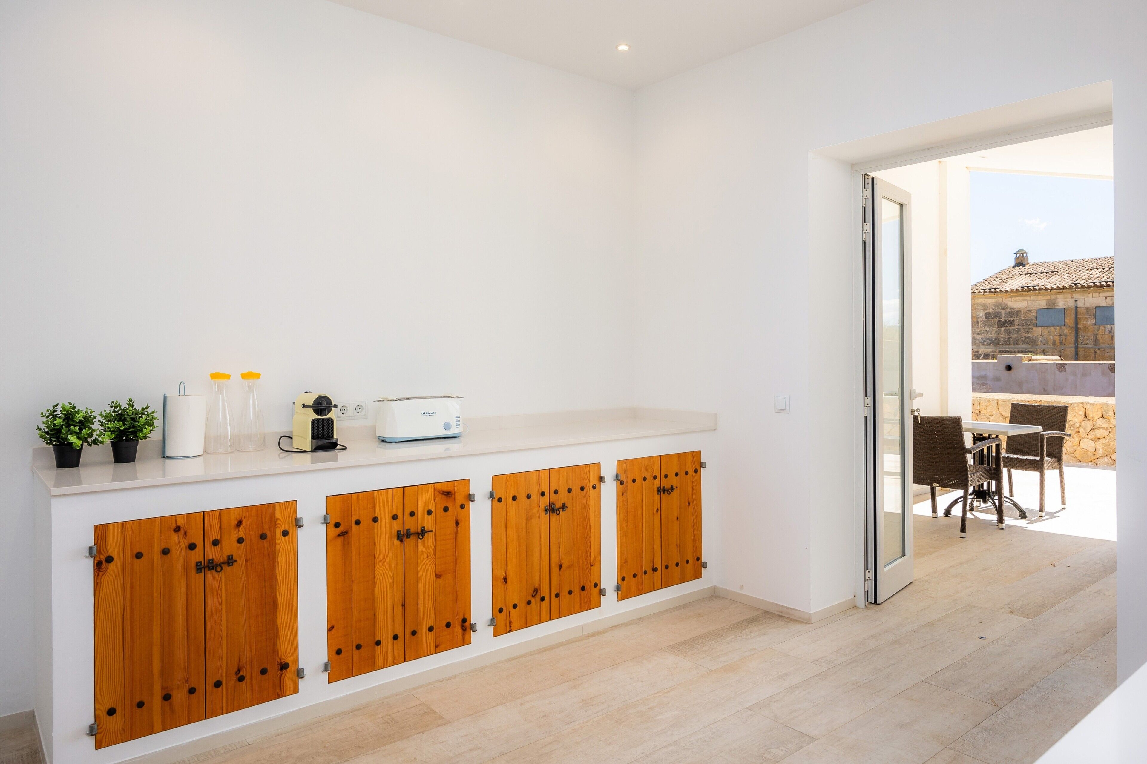 Une cuisine moderne avec des meubles en bois, un plan de travail équipé d’appareils électroménagers et une vue sur une terrasse extérieure.