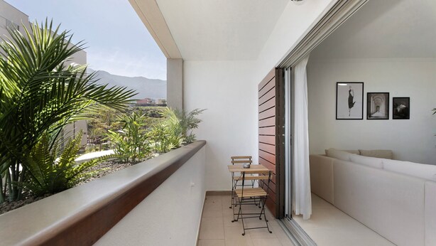 Ein Balkon mit Tisch, Stühlen, einer Sitzecke und Blick auf Berge.
