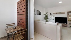 Ein modernes Wohnzimmer mit einer Couch, einem Fernseher und einem kleinen Tisch mit einem Stuhl.