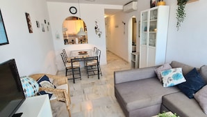 A modern living room with a grey sofa, wicker chair, and a dining area with a table and chairs. - Apartment 'Casa Pals La Cala' with Shared Pool, Wi-Fi and Air Conditioning (La Cala de Mijas)