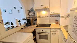 A compact kitchen with white appliances, a built-in oven, a dishwasher, and a sink. - Apartment 'Casa Pals La Cala' with Shared Pool, Wi-Fi and Air Conditioning (La Cala de Mijas)