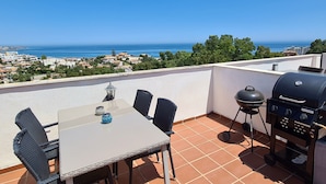 A terrace with a table and chairs, a grill, and a view of the sea and town. - Apartment 'Casa Pals La Cala' with Shared Pool, Wi-Fi and Air Conditioning (La Cala de Mijas)