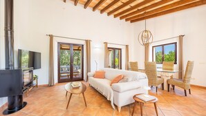 A living room with a sofa, chairs, a TV, and a fireplace. - Holiday Home 'Na Berganta' with Private Terrace, Private Garden and Wi-Fi (Illes Balears)