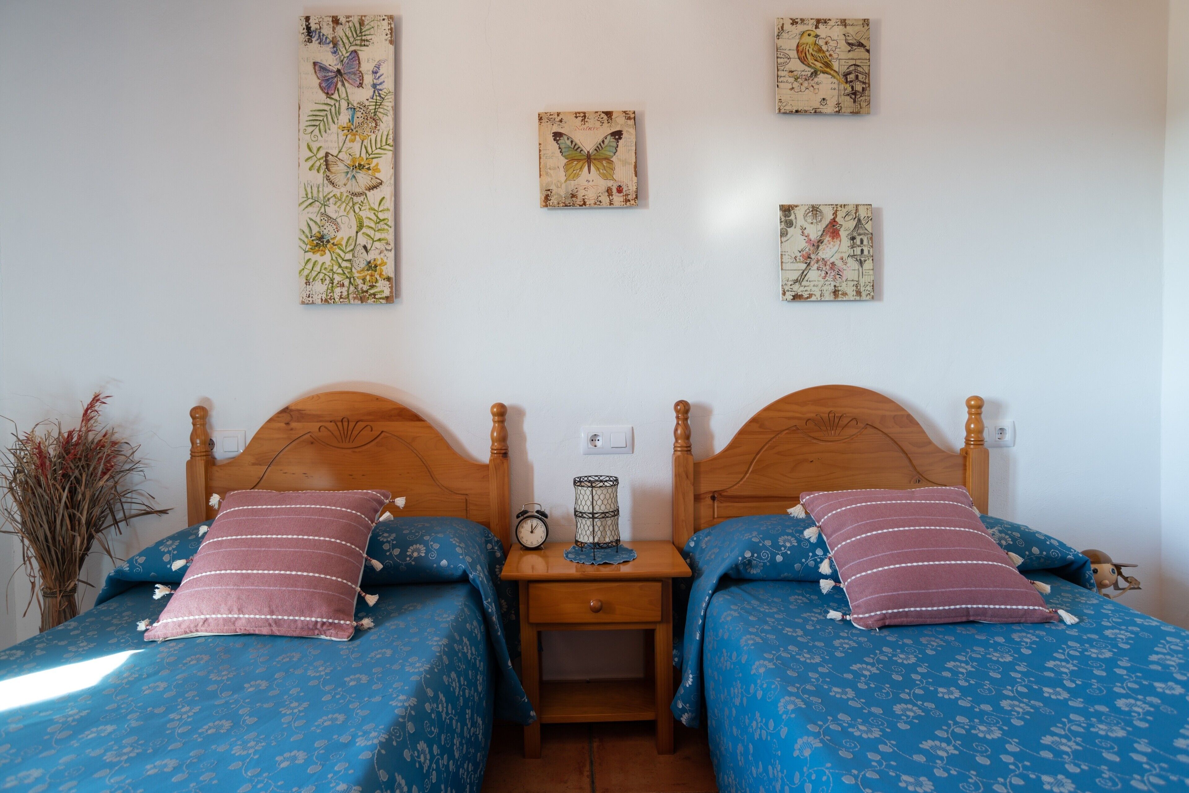 Un dormitorio con dos camas, una mesita de noche y cuadros en la pared.