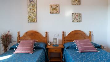 Un dormitorio con dos camas, una mesita de noche y cuadros en la pared.