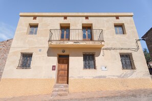 A two-story building with a balcony, a wooden door, and barred windows. - Holiday Home 'Casa Del Practicant' with Mountain Views, Private Terrace and Private Garden (Culla)