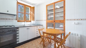 A kitchen with a stove, oven, dining table, chairs, a window, and a cabinet.
