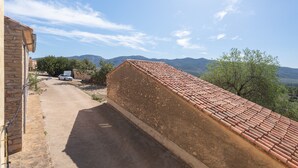 A building with a sloped roof, a paved driveway, and a view of distant mountains.