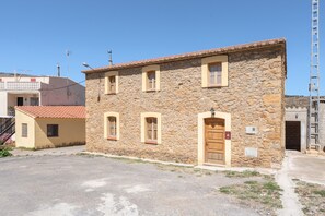A stone building with a tiled roof, a wooden door, and a small window.