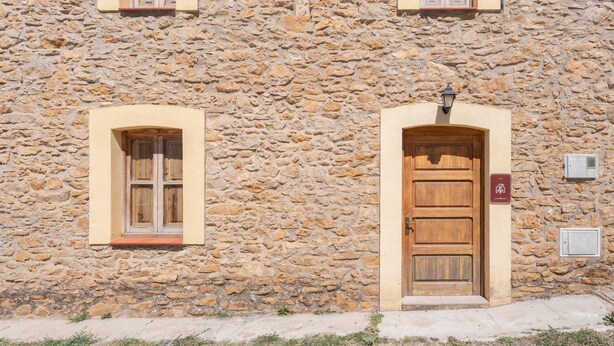 A stone building with two arched windows and a wooden door. - Apartment 'Antiga Escola De Molinell' with Mountain View, Private Terrace and Private Garden (Culla)
